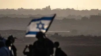 Una bandera israelí borrosa ondea junto a los soldados. Gaza al fondo.